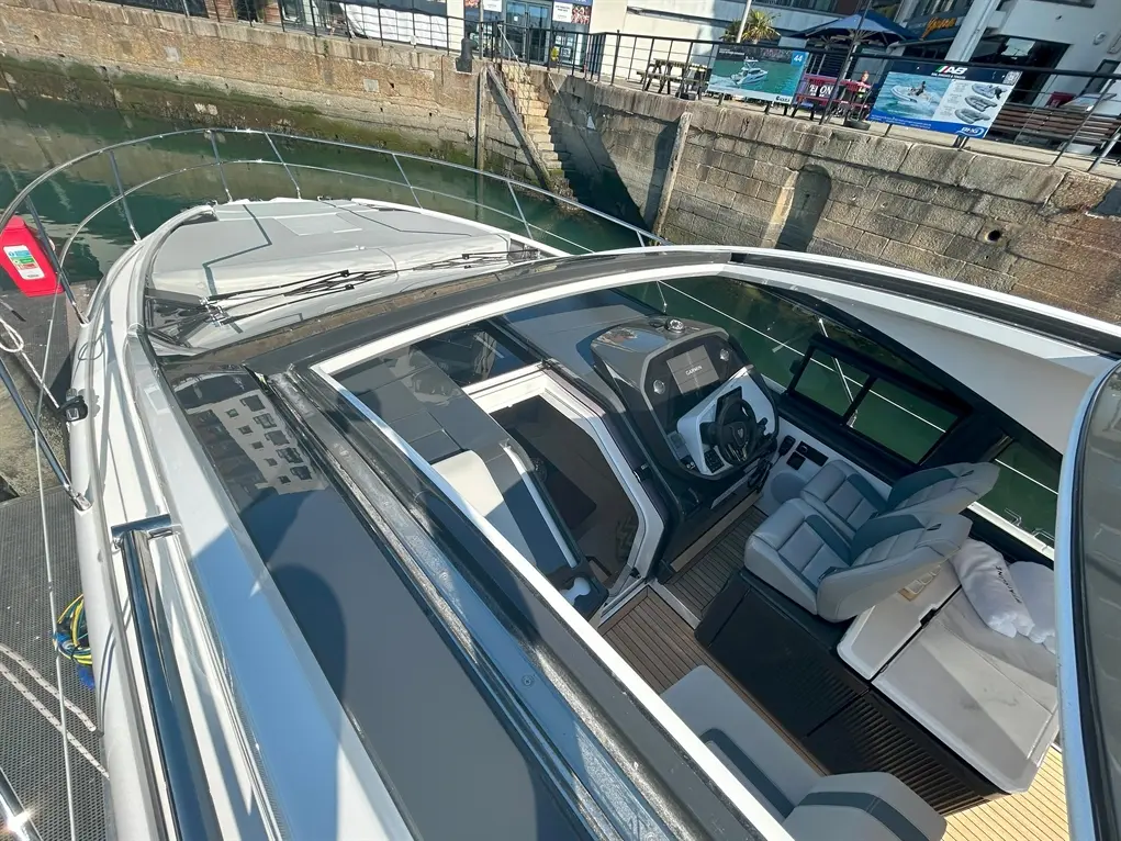 Luxury motorboat cockpit viewed from above, showcasing seating, steering console, and waterway background.